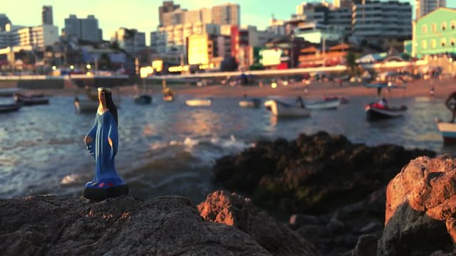 A small statue of Yemanja stands on the rocks at Rio Vermelho during a celebration in the honor of the Queen of the Sea in Salvador, Bahia, Brazil