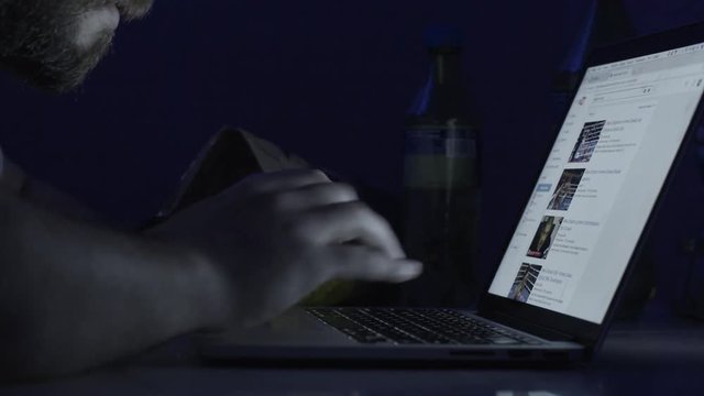 Young man working on computer at night in dark room. The designer works in the later time. Man working on laptop in the dark
