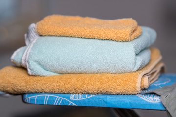 Stack of folded cotton bath towels on ironing board