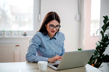Beautiful elegant young woman with eyeglasses using laptop computer.