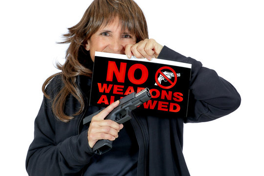 Middle Aged Woman holding a No Weapons Sign and a Handgun