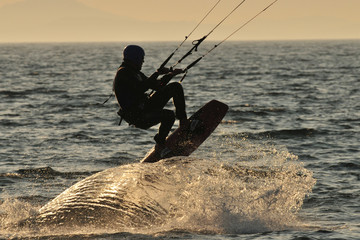 Naklejka premium Kitesurfer creating a wave while jumping