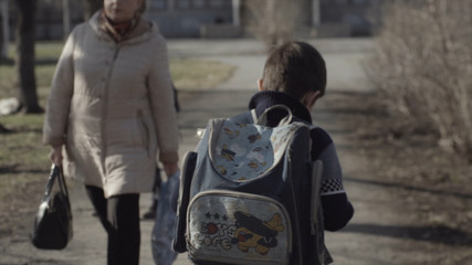Little boy with a backpack go to school. Back view. Boy with a backpack walking in the Park. Concept of lonely