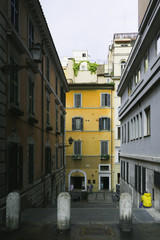 Light showing man with yellow jacket sitted between buildings in a public roman street