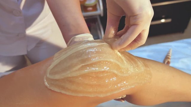 Sugaring epilation skin care with liquid sugar at legs