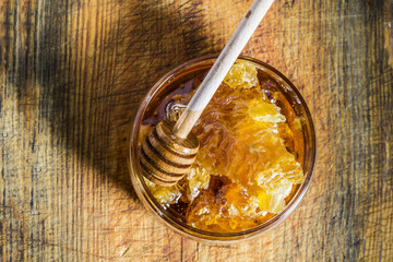 Fresh honey jar and dipper stick on a wooden board with herb - dripping honey