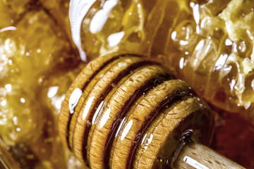 Fresh honey jar and dipper stick on a wooden board with herb - dripping honey