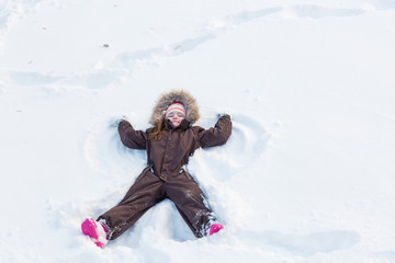 Fototapeta na wymiar Beautiful little girl playing in freshly fallen snow in winter park