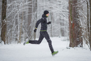Fototapeta na wymiar Photo from side of man in sports clothes on run in winter
