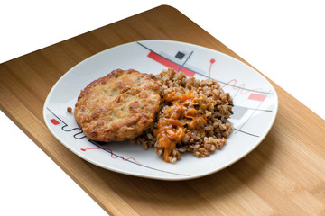 Buckwheat porridge with a cutlet on a white plate. Buckwheat cereal with schnitzel on a wooden board.
