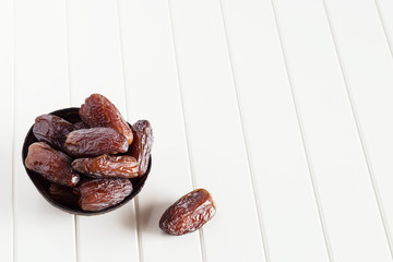 Fresh dates Medjool in wooden coconut bowl. White background.