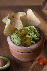 guacamole with lime and chili pepper on a rustic table