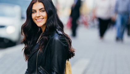 Young pretty latin woman walking near shops in city centre