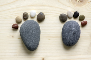 Obraz na płótnie Canvas Two tiny stone feet and ten toes on wooden background, stone in the shape of a human feet