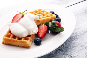 Plate of belgian waffles with whipped cream and fresh berries