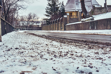 The snow-covered road descends in the city between private houses