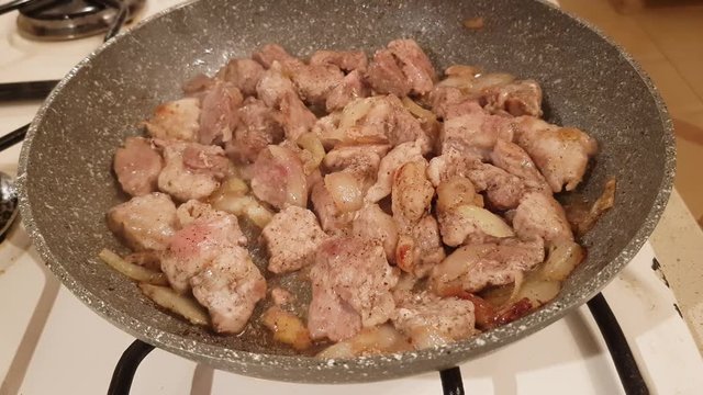 Finely chopped pieces of pork with onion and spices fry in oil on the stove
