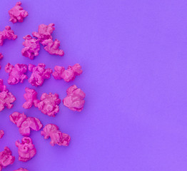 Pink popcorn on purple paper background. Fashion pop art style. Top view.