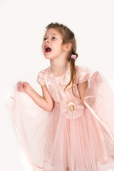 The girl in a pink ball dress and with blue eyes stands at a wall. She is capricious;