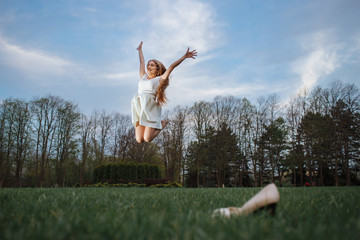 Young woman jumping barefoot on green meadow. Freedom and health in megapolice concept