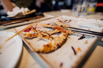 Close up focus view of wasted food of pizza on the plate after lunch.