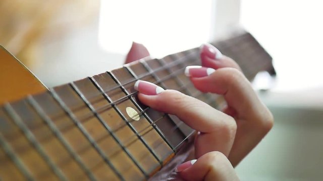 woman's hands playing acoustic guitar, close up