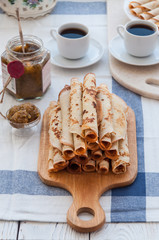 Fototapeta premium Thin pancakes for breakfast. Maslenitsa. On the table, a dish with pancakes, coffee and jam from feijoa