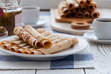Thin pancakes for breakfast. Maslenitsa. On the table, a dish with pancakes, coffee and jam from feijoa