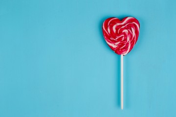 Sweet bright lollipop heart on blue background. Love concept, Valentine day