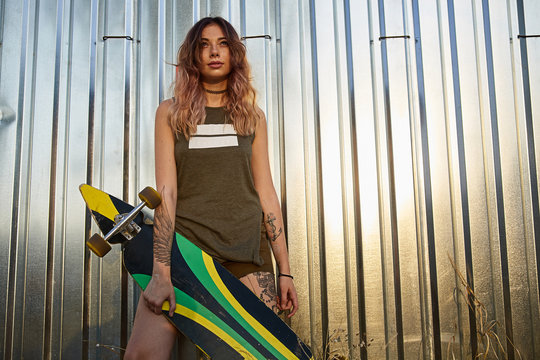 Girl with tattoos posing with longboard