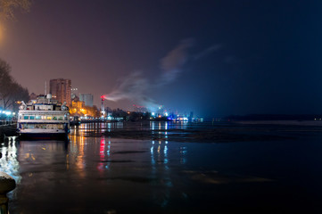 Fototapeta na wymiar Night view from the embankment of Rostov-on-Don on river Don to the east. River cruise ship in winter mooring