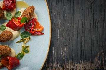 Vegan falafel medallion with roasted pepper and hummus over rustic table, copy space
