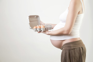 Pregnant woman holding eggs - studio shot