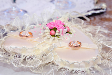 Wedding rings lie on a beautiful embellished rhinestone pillow