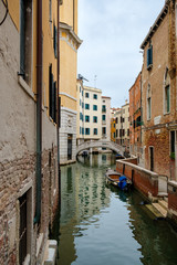 Fototapeta na wymiar Narrow canal surrounded by old palaces in Venice