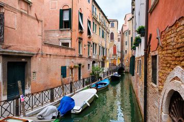 Fototapeta na wymiar Narrow canal surrounded by old decaying buildings in Venice