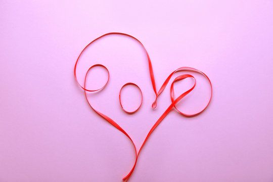 Word LOVE made of ribbons on color background