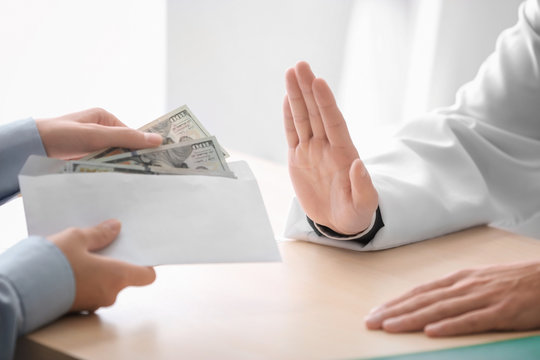 Doctor refusing to take money in envelope at table. Corruption concept