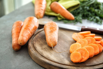 Wooden board with sliced carrot on table, closeup