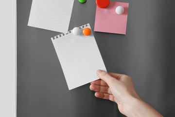 Woman touching paper sheet on refrigerator door