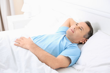 Obraz na płótnie Canvas Mature man lying on white pillow indoors