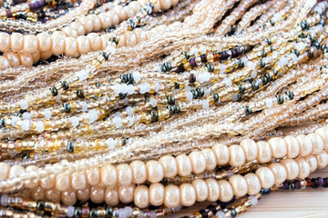 Multicolor beads. Nice, brown, dark yellow and beige beads on old wooden colored background. An old style vintage background. Selective soft focus.