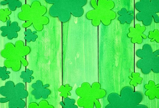 St Patricks Day frame of shamrocks over a green wood background