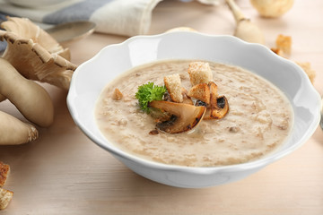 Bowl with delicious mushroom soup on wooden table