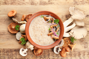 Bowl with delicious mushroom soup on wooden table