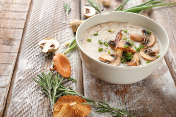 Bowl with delicious mushroom soup on wooden table