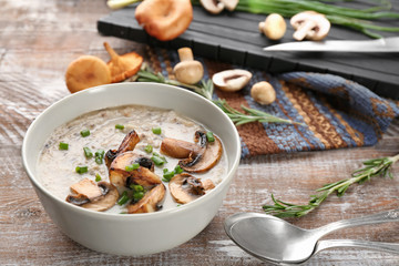 Bowl with delicious mushroom soup on wooden table