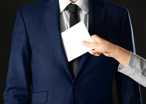 Woman putting bribe in businessman's pocket, closeup