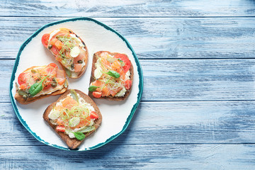 Tasty bruschettas with salmon, mozzarella and prosciutto on plate