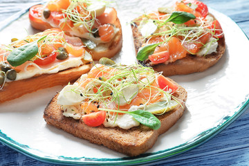 Tasty bruschettas with salmon, mozzarella and prosciutto on plate